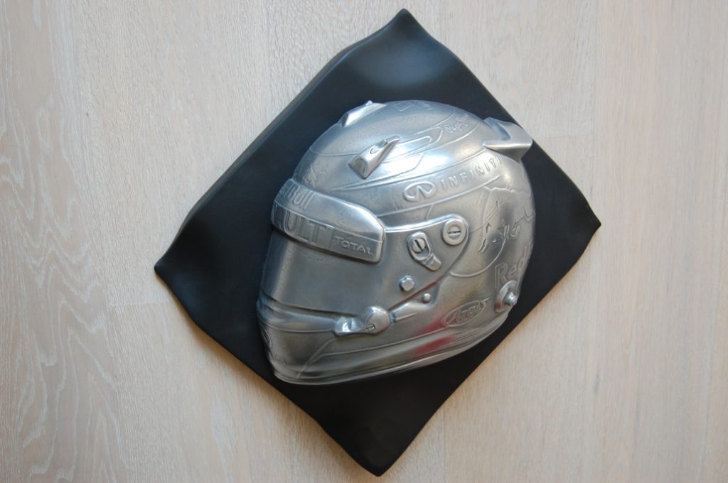 Gegossener Rennfahrerhelm-Abdruck auf schwarzer Dekorplatte mit Metalllackierung – Sonderanfertigung der Tischlerei Cluse