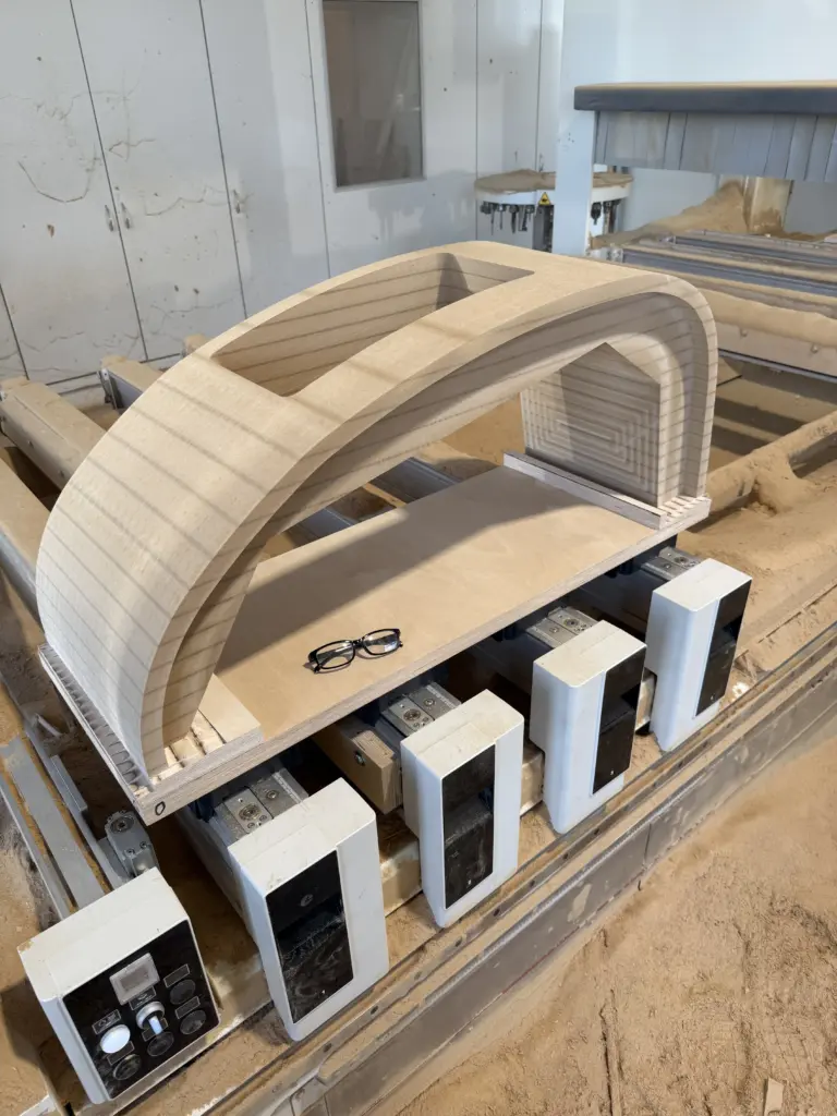 CNC-gefräster Holzbogen auf der Fräsmaschine mit Spannvorrichtungen – Holz-Sonderanfertigung der Tischlerei Cluse